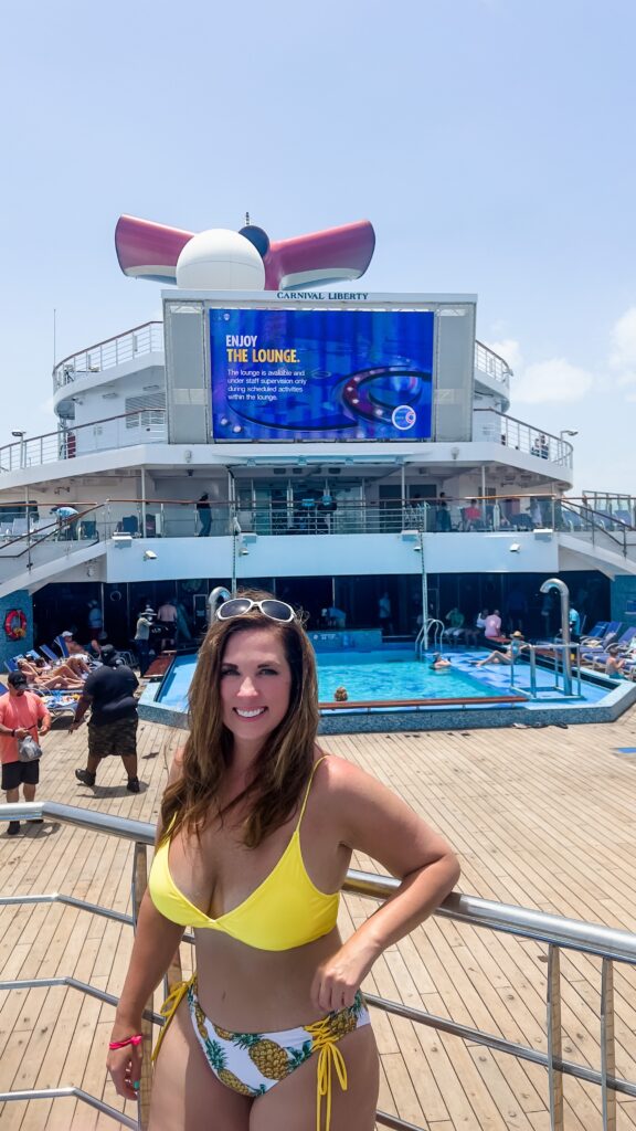 A woman in a yellow bathing suit posing on the lido deck on the Carnival Sunshine cruise ship.