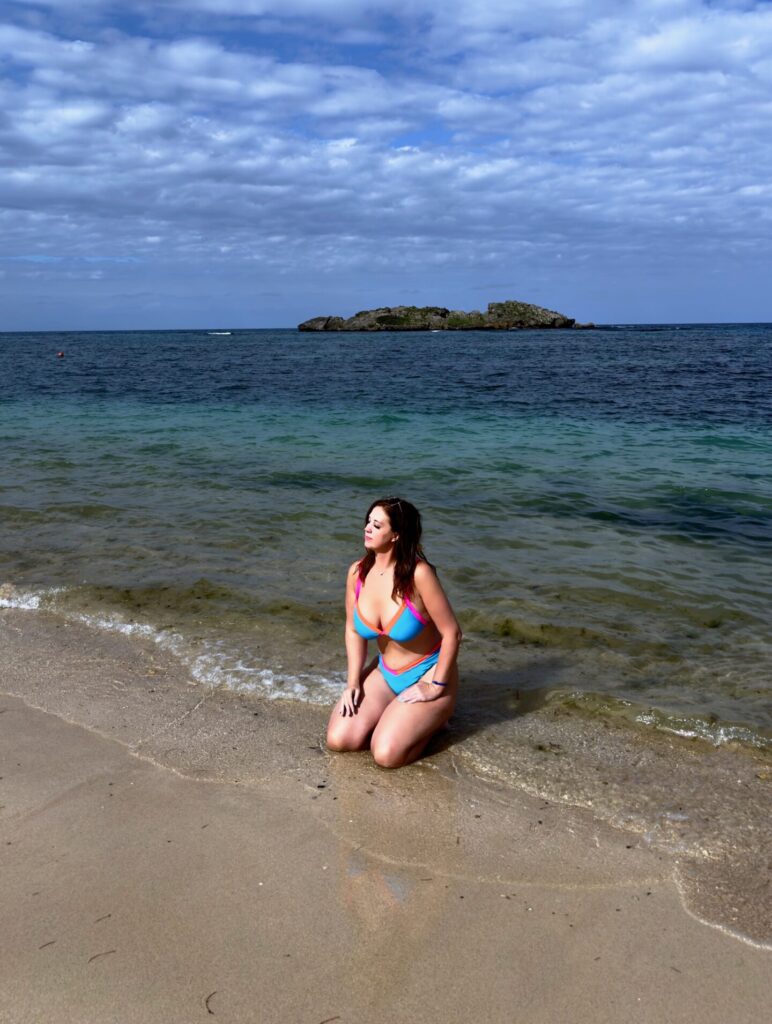 A woman kneels in the ebbing ocean tide at Cosita Rica beach in Puerto Plata, Dominican Republic