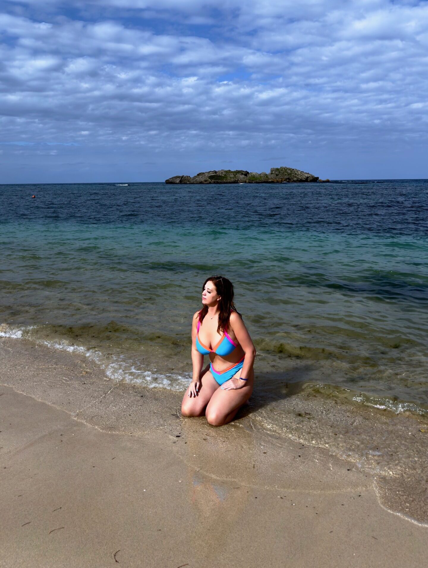A woman kneels in the ebbing ocean tide at Cosita Rica beach in Puerto Plata, Dominican Republic