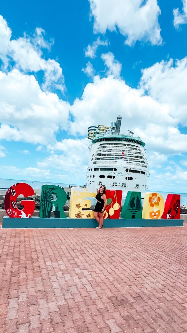 Professor Melissa posing in front of a colorful "Grenada" sign at the St. George cruise port with Royal Carribean's Explorer of the Seas