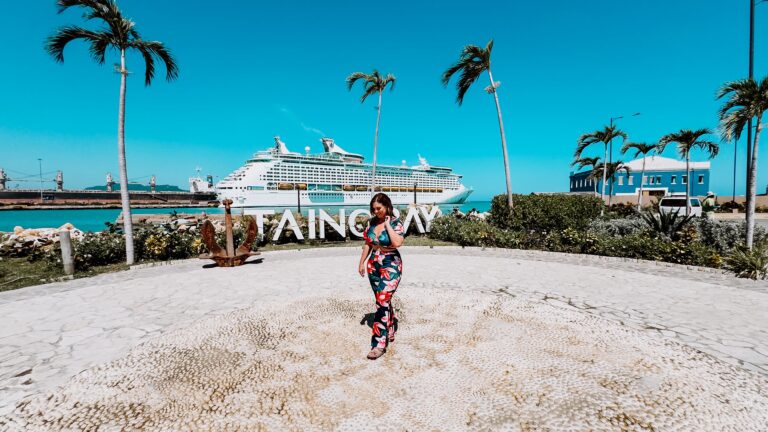 A woman stands in front of the Taino Bay sign and Royal Caribbean's Explorer of the Seas cruise ship at Port Taino Bay in Puerto Plata, Dominican Republic