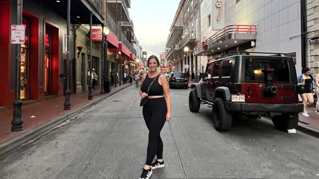 A woman stands in the middle of Bourbon Street in New Orleans.