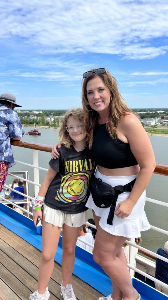A woman and her daughter pose on a cruise ship deck at Port NOLA as it sails down the Mississippi River.