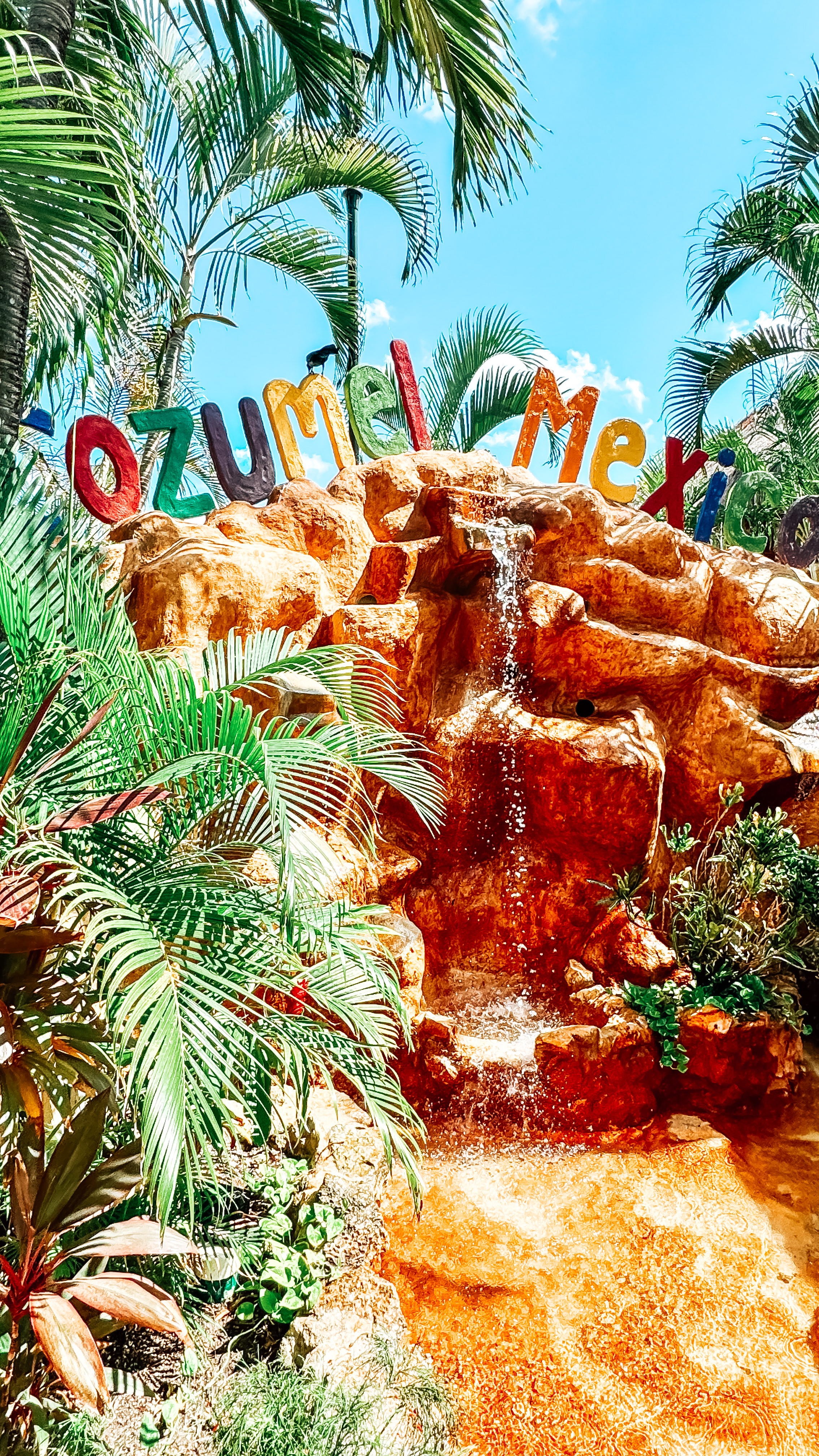 A waterfall in Mexico with "Cozumel" in colorful letters across the top