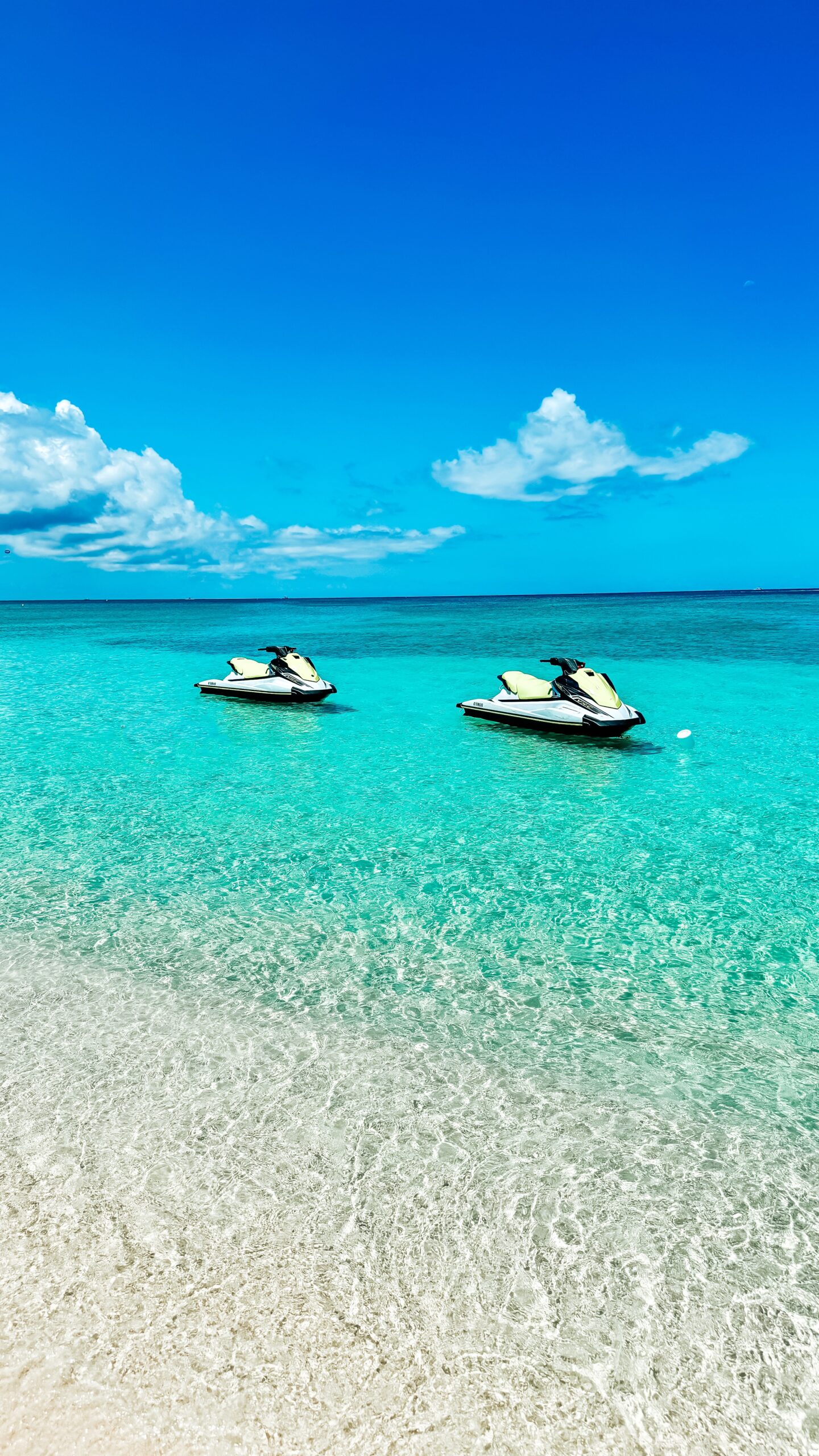 Jet skis sit waiting for renters in the shallow waters of Seven Mile Beach in Grand Cayman