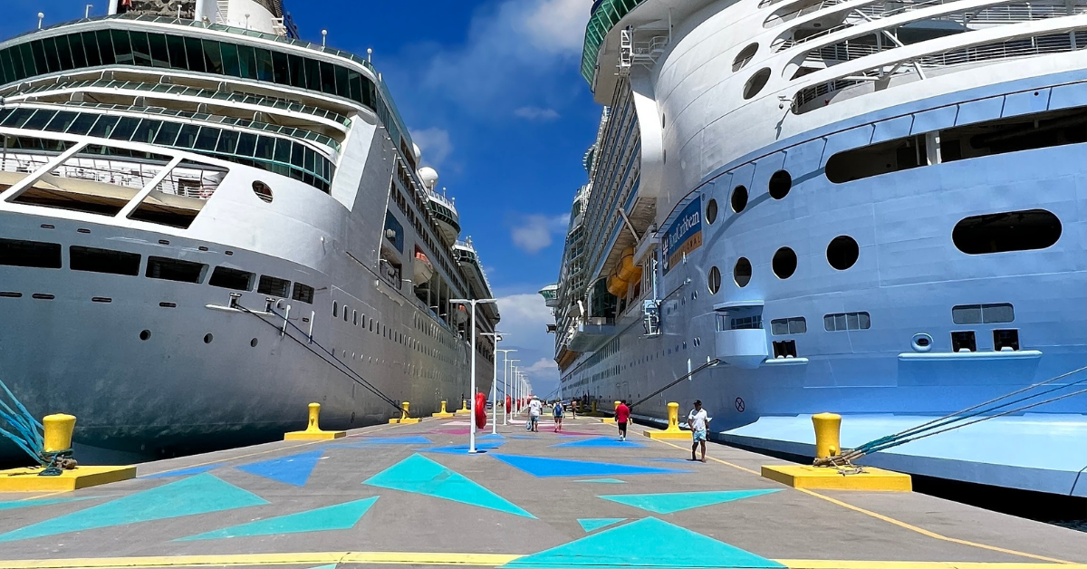 A vibrant dock scene featuring two large Royal Caribbean cruise ships docked side by side.