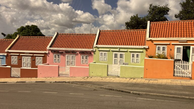 Four colorful houses are lined up on a street in Curacao, which is known for its picturesque, colorful colonial architecture.