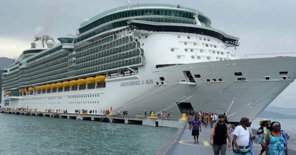 A large group of people walking along a dock beside the enormous "Independence of the Seas" cruise ship.