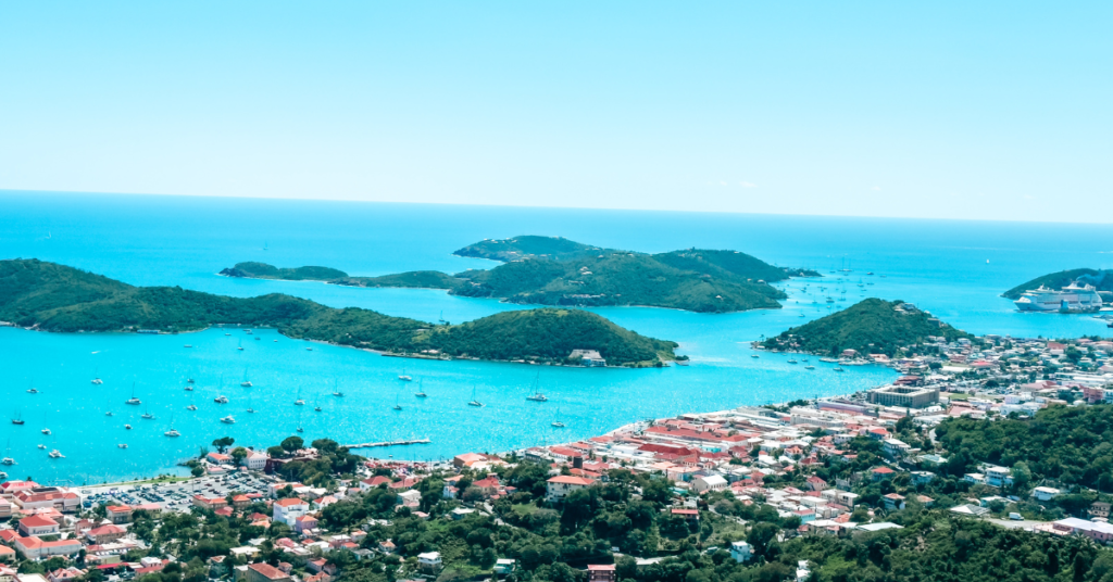 A panoramic view of an island landscape with turquoise blue waters and scattered boats.