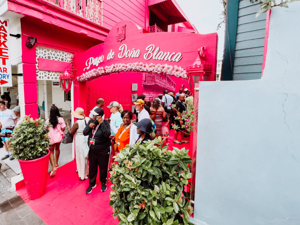 Tourists crowd the vibrant pink alley of Paseo Dona Blanca in Puerto Plata.