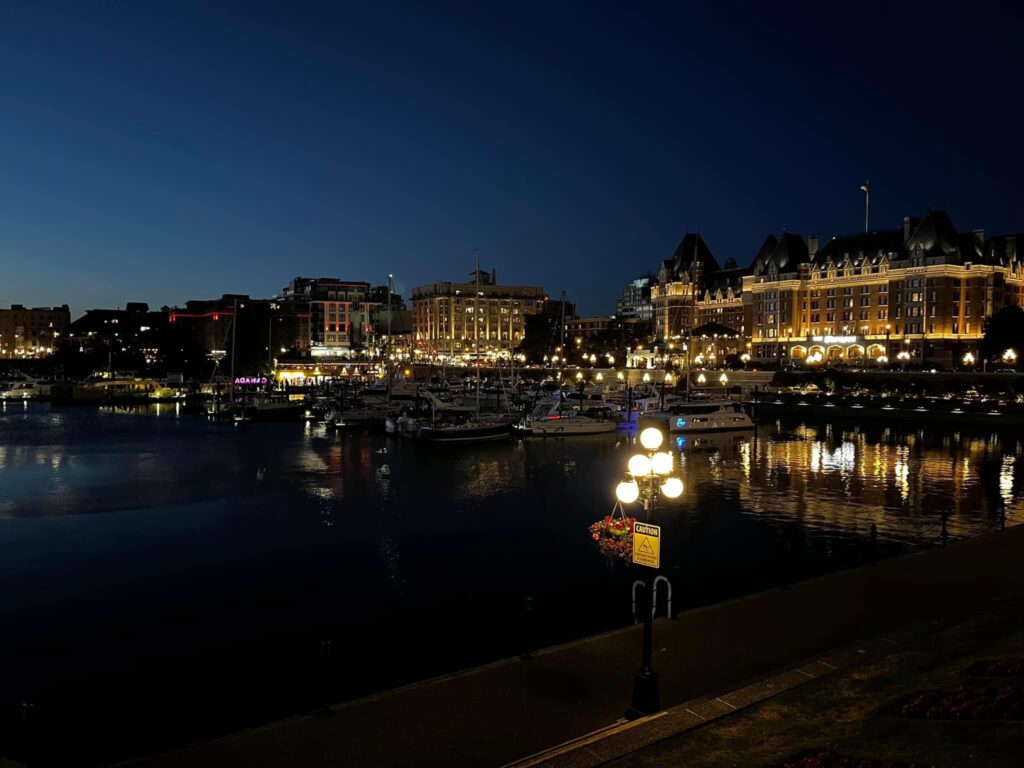 A picturesque harbor scene at night, with various buildings illuminated along the waterfront