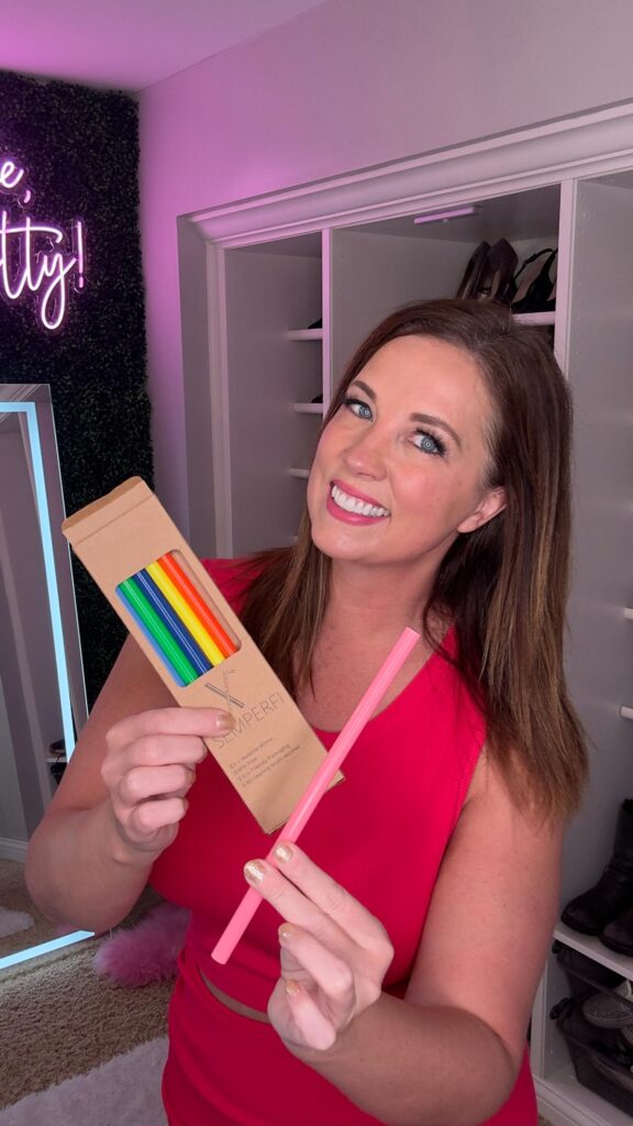 A woman smiling holding a colorful reusable straw