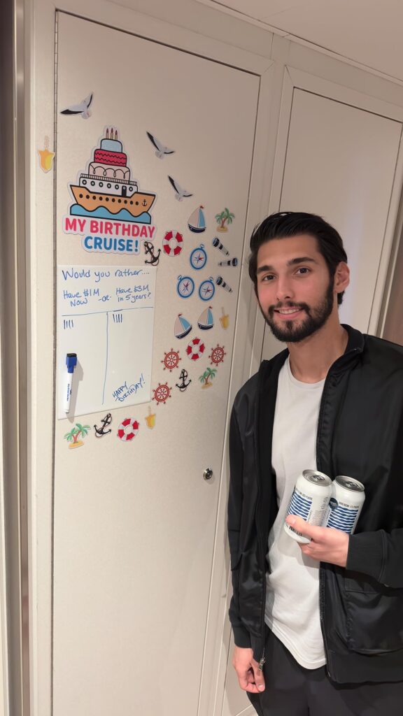 A man holding a can of drinks beside a colorful magnets and whiteboard